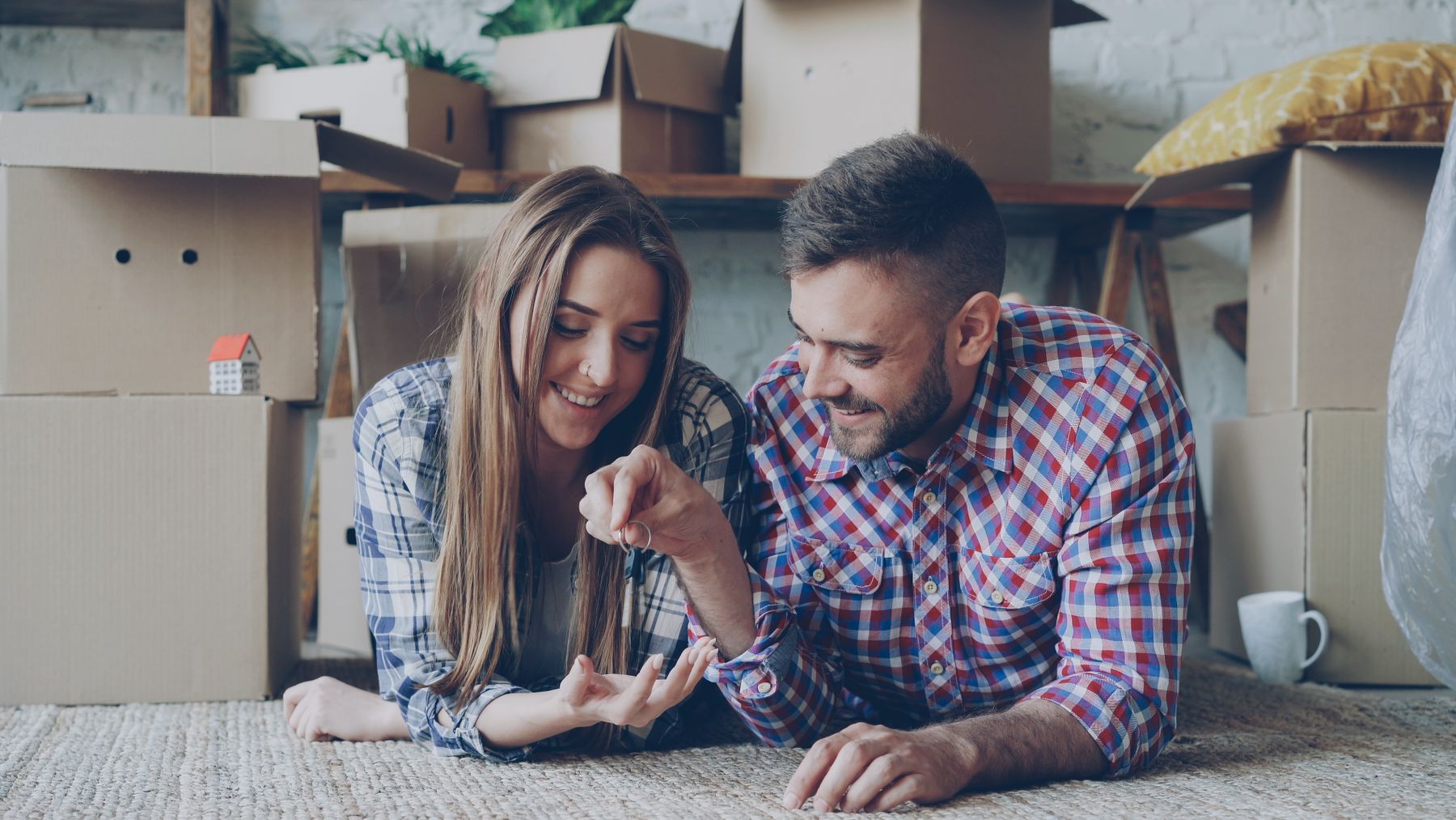 A happy couple holding their new keys among moving boxes