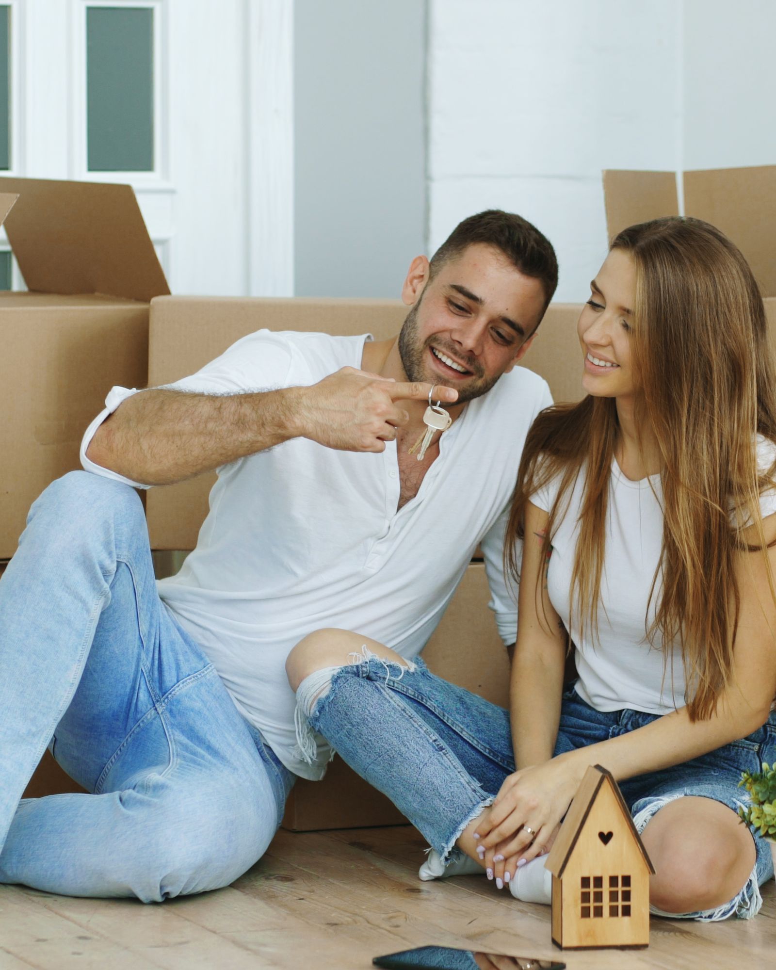 A couple carrying boxes as they move into a home
